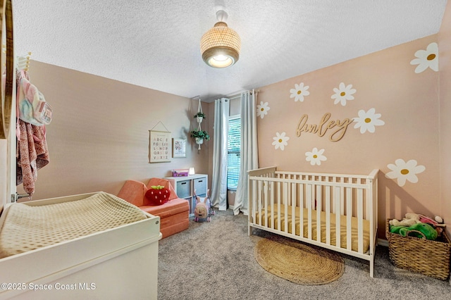 bedroom featuring a textured ceiling, carpet floors, and a crib