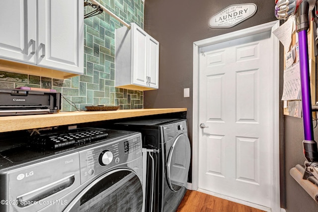 laundry room with light wood-type flooring, cabinet space, and washing machine and dryer