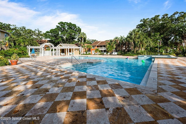 view of pool featuring a pool with connected hot tub, a patio, and a pergola