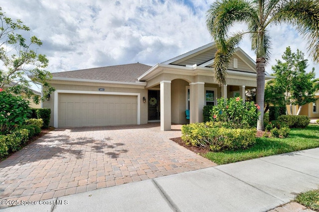 view of front facade featuring decorative driveway, an attached garage, and stucco siding