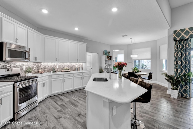 3465 Diamond Leaf Dr, Vero Beach, FL 32966 - kitchen featuring stainless steel appliances, a breakfast bar, a sink, visible vents, and tasteful backsplash