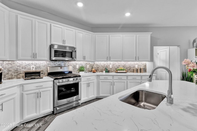 3465 Diamond Leaf Dr, Vero Beach, FL 32966 - kitchen featuring decorative backsplash, appliances with stainless steel finishes, white cabinets, a sink, and light stone countertops