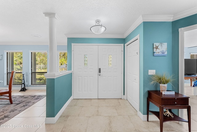 entrance foyer featuring crown molding, baseboards, ornate columns, and a textured ceiling