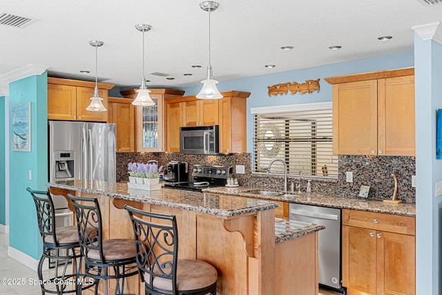 kitchen with visible vents, a breakfast bar, a sink, a center island, and stainless steel appliances