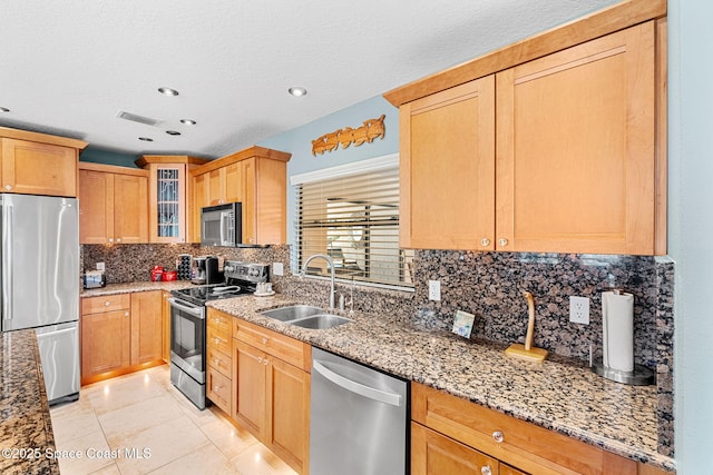 kitchen featuring visible vents, light stone countertops, stainless steel appliances, and a sink