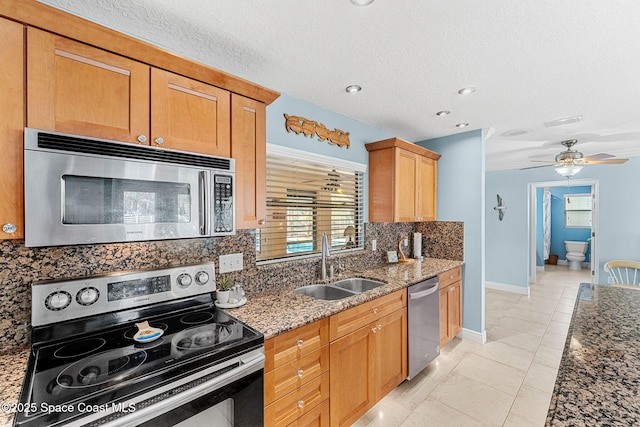 kitchen featuring a wealth of natural light, light stone countertops, appliances with stainless steel finishes, and a sink