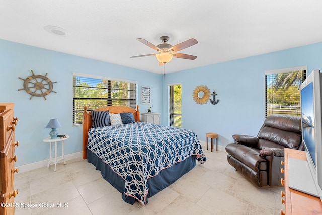 bedroom featuring multiple windows, a ceiling fan, and baseboards