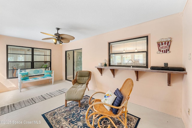 living area featuring a textured ceiling and a ceiling fan