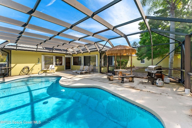 outdoor pool with glass enclosure, a patio, and grilling area