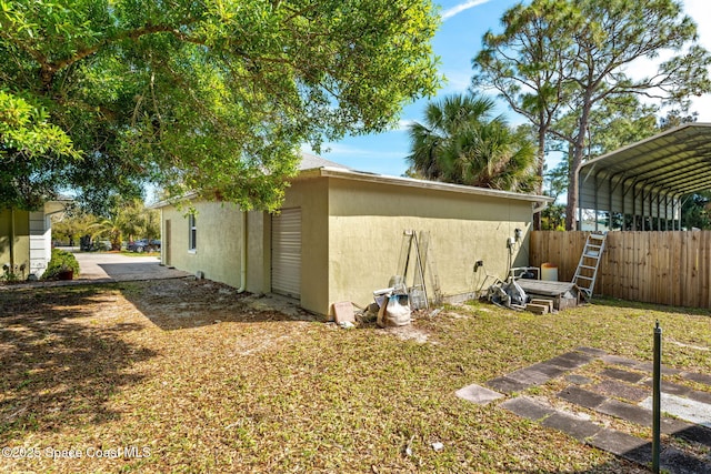 view of property exterior featuring a carport, fence, and stucco siding