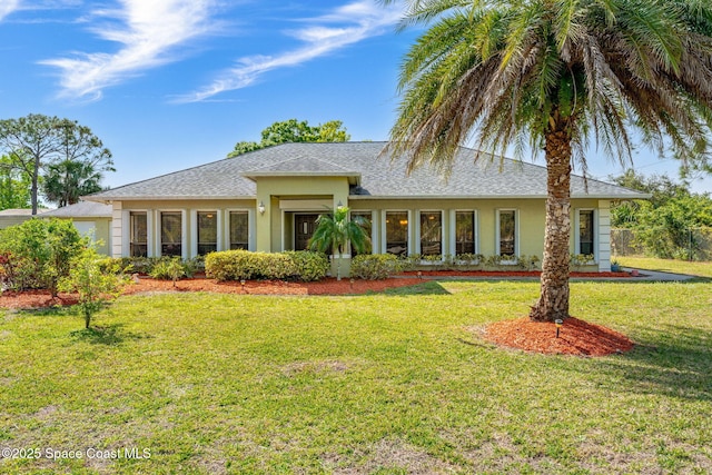 view of front facade with stucco siding, a front yard, and a shingled roof