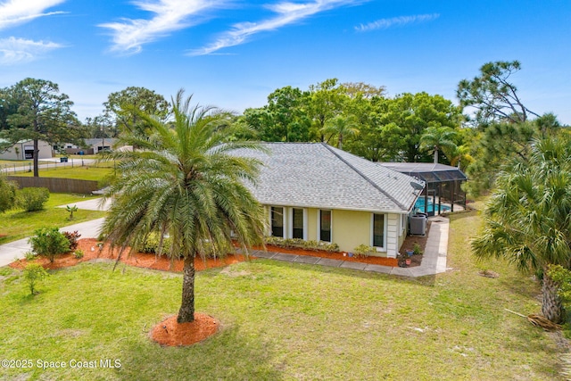 view of front of property featuring glass enclosure, a front yard, and roof with shingles