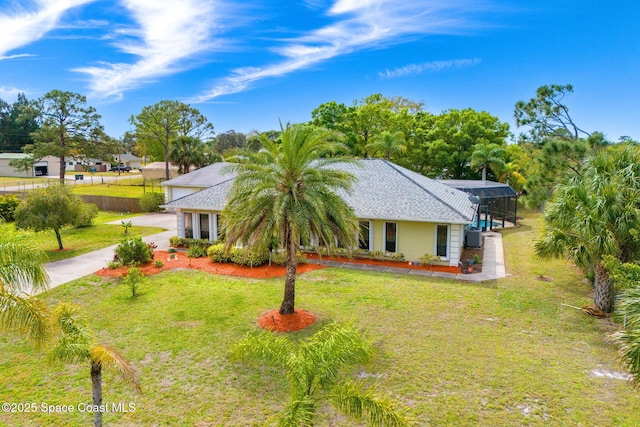 view of front of property with a lanai, a front yard, and roof with shingles