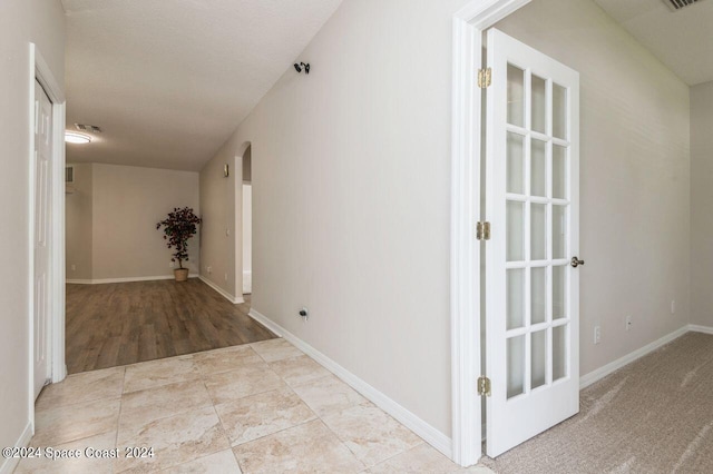 hall featuring arched walkways, tile patterned flooring, and baseboards