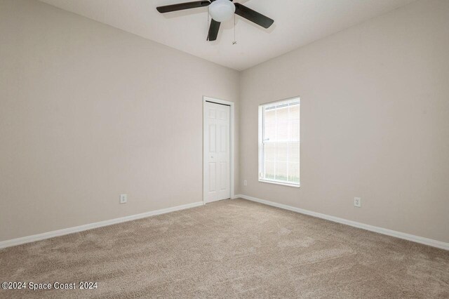 carpeted empty room featuring ceiling fan and baseboards