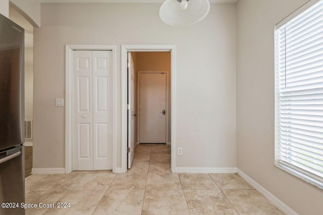 spare room featuring baseboards, light tile patterned floors, and a healthy amount of sunlight