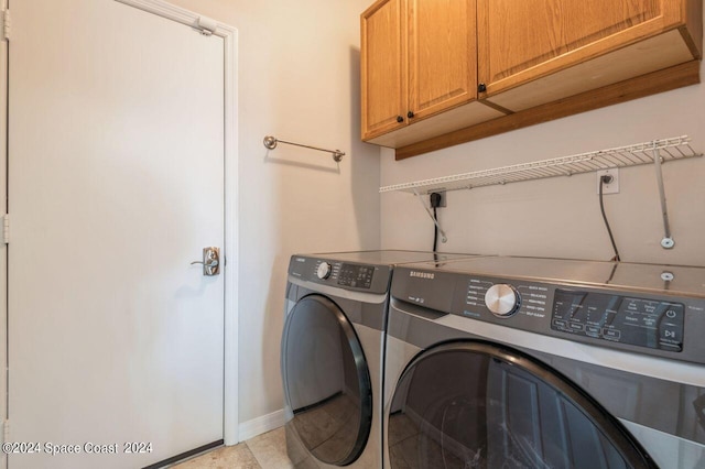 laundry area with washing machine and dryer, cabinet space, and baseboards