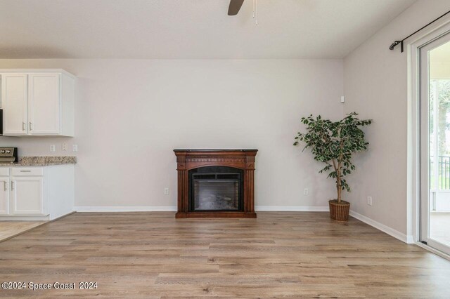 unfurnished living room featuring light wood-style floors, ceiling fan, a fireplace, and baseboards