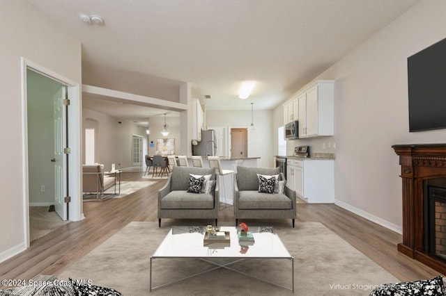 living area with baseboards, a fireplace, and light wood-style floors