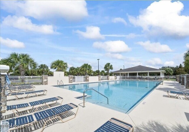 community pool with a patio and fence