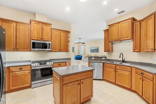 kitchen featuring visible vents, a sink, appliances with stainless steel finishes, dark countertops, and a center island