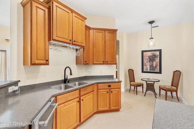 kitchen with baseboards, a sink, pendant lighting, stainless steel dishwasher, and dark countertops