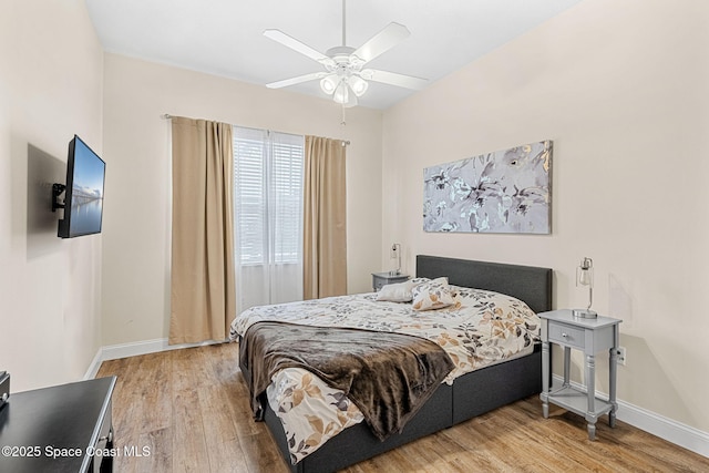 bedroom featuring baseboards, light wood finished floors, and ceiling fan