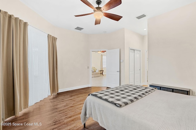 bedroom featuring baseboards, wood finished floors, visible vents, and ceiling fan