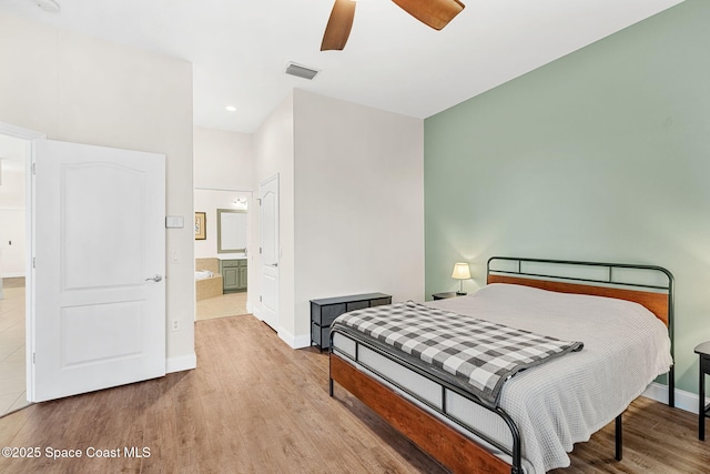 bedroom with visible vents, baseboards, wood finished floors, and ensuite bathroom