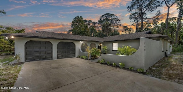 ranch-style home with a garage, concrete driveway, and stucco siding