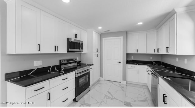 kitchen with dark countertops, marble finish floor, and appliances with stainless steel finishes