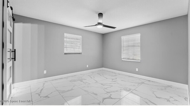 spare room with marble finish floor, baseboards, and a ceiling fan