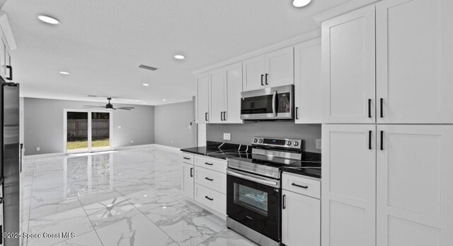 kitchen with visible vents, white cabinets, appliances with stainless steel finishes, dark countertops, and marble finish floor