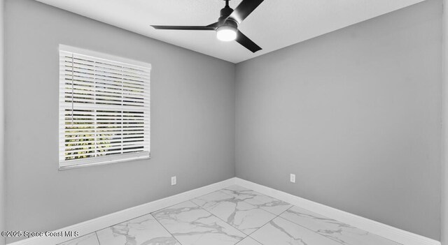 unfurnished room with a ceiling fan, baseboards, and marble finish floor