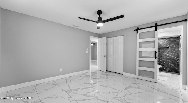 unfurnished bedroom featuring visible vents, marble finish floor, a barn door, a closet, and baseboards