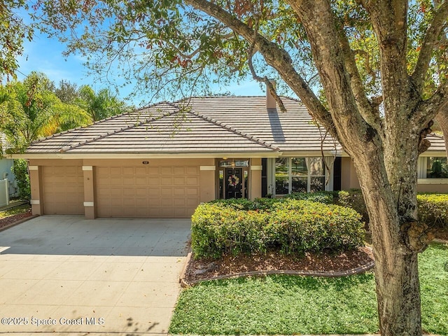 ranch-style house with driveway, a tile roof, an attached garage, and stucco siding