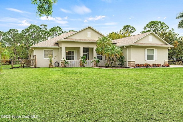 view of front of home with covered porch, fence, a front lawn, and stucco siding