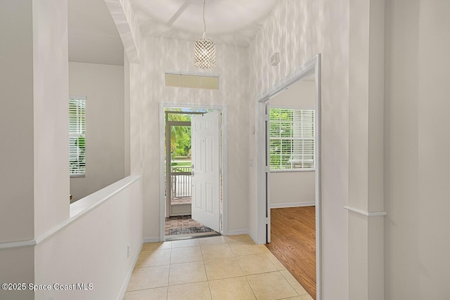 doorway featuring tile patterned flooring, a wealth of natural light, and baseboards