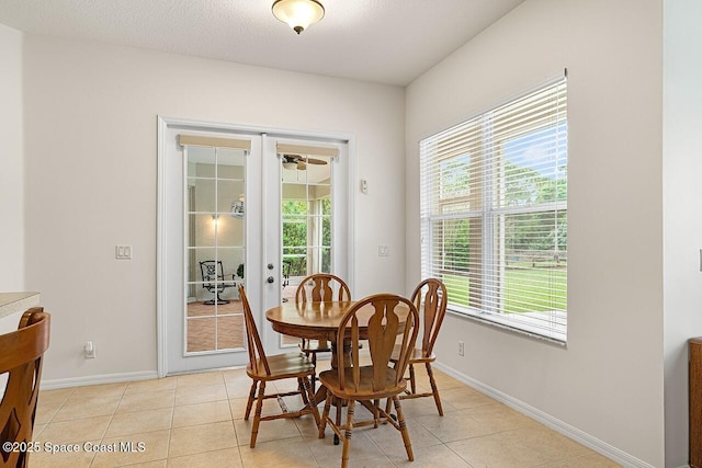 dining area featuring light tile patterned floors, baseboards, a textured ceiling, and french doors