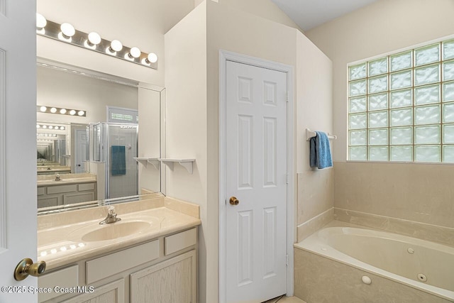 bathroom with a shower stall, a tub with jets, and vanity