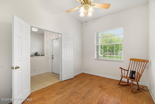 sitting room featuring baseboards, ceiling fan, and light wood finished floors