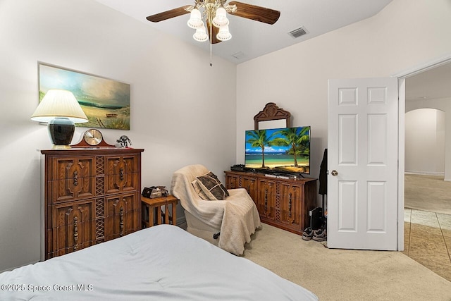 bedroom featuring light carpet, visible vents, arched walkways, ceiling fan, and vaulted ceiling