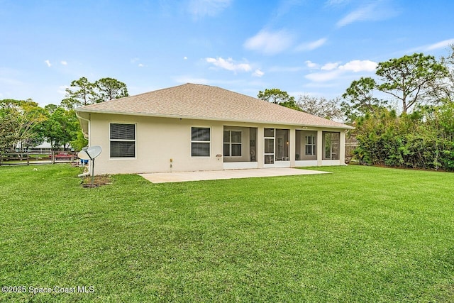 back of property with a shingled roof, stucco siding, a patio, and a lawn