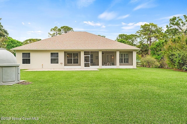 rear view of house with stucco siding, a shingled roof, a sunroom, and a yard