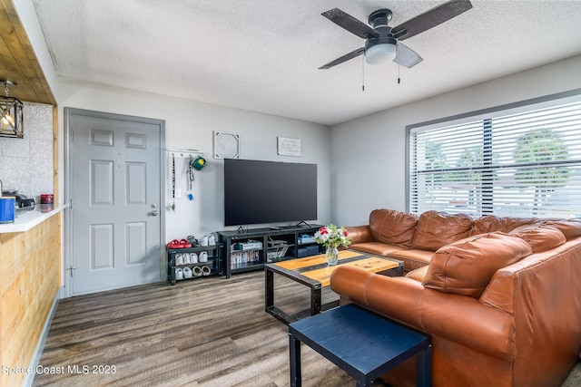 living room featuring a textured ceiling, ceiling fan, and wood finished floors