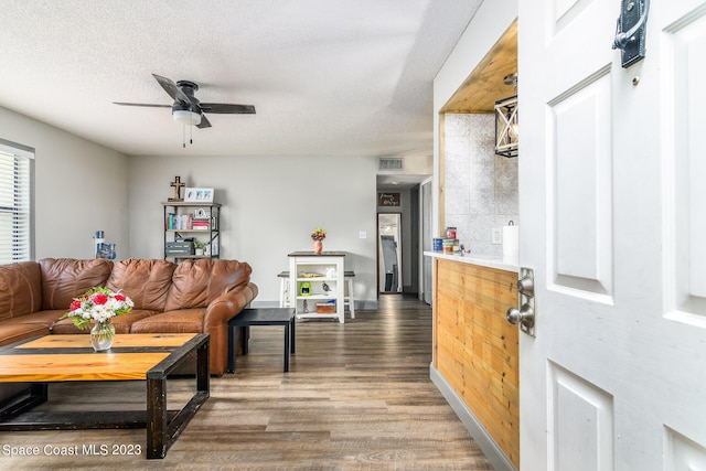 living room featuring baseboards, visible vents, ceiling fan, wood finished floors, and a textured ceiling