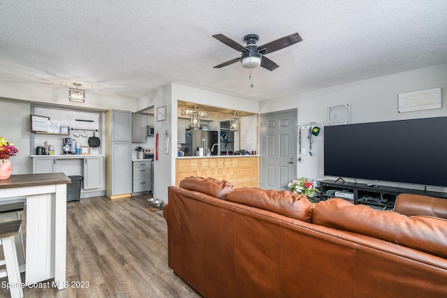 living room featuring ceiling fan, a textured ceiling, and wood finished floors