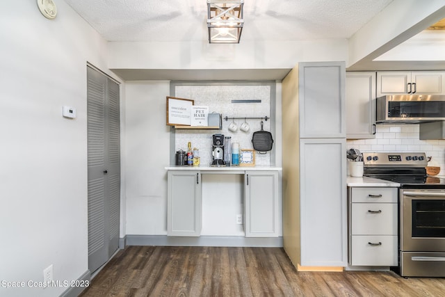 kitchen with tasteful backsplash, wood finished floors, stainless steel appliances, a textured ceiling, and light countertops