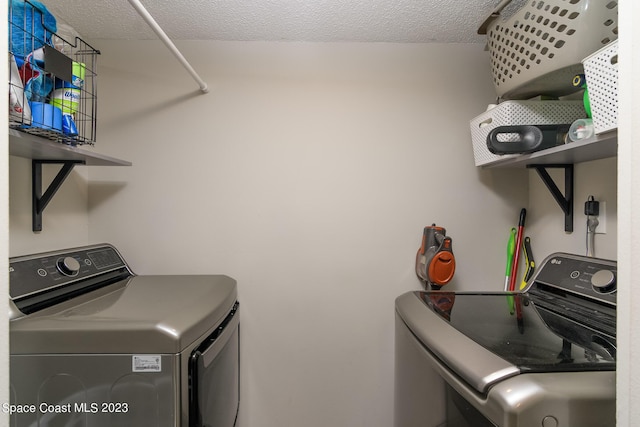 washroom featuring a textured ceiling, laundry area, and separate washer and dryer