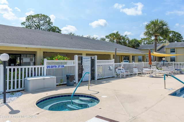 view of swimming pool featuring a community hot tub, a patio area, and fence